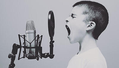 Junge mit weit aufgerissenem Mund vor Mikrofon