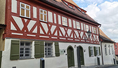 Außenansicht eines historischen Fachwerk-Gebäudes mit grünen Fensterläden.