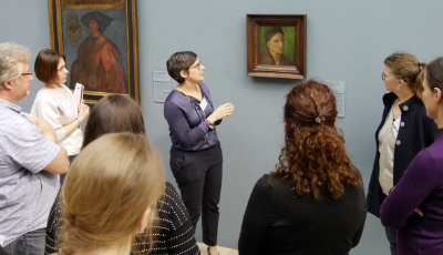 Erwachsene stehen bei einer Führung in einer Ausstellung um ein Portrait.